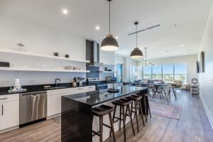 a kitchen with white cabinets and a large island with bar stools at Elegant 4 BR Luxury Condo with Rooftop Pool Next to the Hangout in Gulf Shores