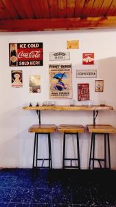 a counter with two stools against a wall with posters at Hostel Piltri in El Bolsón