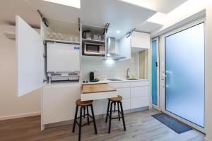 a kitchen with white cabinets and a counter with stools at Estúdio Cândida, One place … in Nazaré