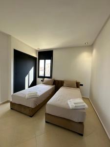a bedroom with two beds and two windows at Luxury appartement Fes in Fez