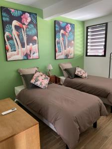 2 Betten in einem Zimmer mit grünen Wänden in der Unterkunft Le CAILLOU in La Trinité