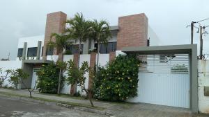 een wit huis met een poort en een palmboom bij Casa Aruana in Aracaju