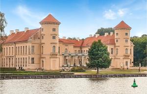 a large castle with a lake in front of it at Cozy Ship In Rheinsberg Hafendorf With House Sea View in Rheinsberg