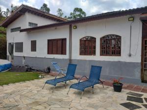 3 chaises bleues assises sur une terrasse en face d'une maison dans l'établissement Recanto Kamei-Piscina climatizada, à São Roque