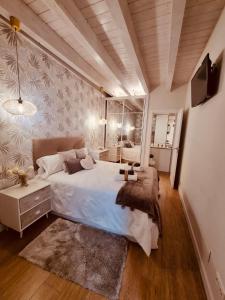 a bedroom with a large white bed and a tv at BELLA VISTA Catedral-Apartamentos Burgos Catedral in Burgos