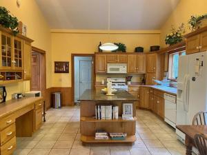 a large kitchen with wooden cabinets and a white refrigerator at Highland Woods - Private home on 37 acres with stunning mountain views in Shaftsbury