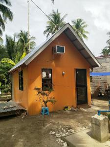 uma pequena casa laranja com uma árvore em frente em Small cosy house (simple but complete) em Asgad
