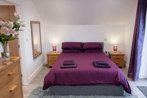a bedroom with a purple bed with two dressers and a mirror at Chy Lowen, great valley views from balcony in Hayle
