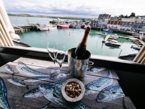 a bottle of wine sitting on a table next to a window at Padstow Escapes - Pajar Luxury Penthouse Apartment in Padstow