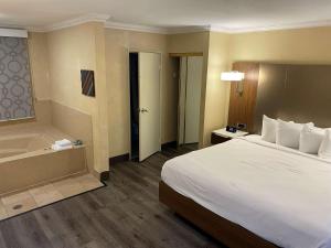 a hotel room with a bed and a bath tub at Best Western Hollywood Plaza Inn Hotel - Hollywood Walk of Fame LA in Los Angeles