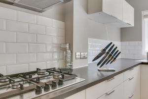 a kitchen with a stove and white tiles at Boutique Victorian 4 Bed House with Garden in Balham in London