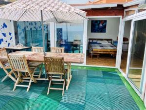 a wooden table with chairs and an umbrella on a patio at Atico de la Pardela in Las Lagunas