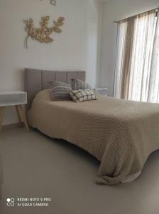 a bedroom with a bed with a blanket and a window at Condominio Palomino en Viñedos del Mar Ensenada privada San Antonio in Ensenada