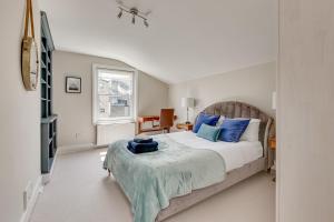 a bedroom with a bed with blue pillows and a television at Boutique Victorian 4 Bed House with Garden in Balham in London