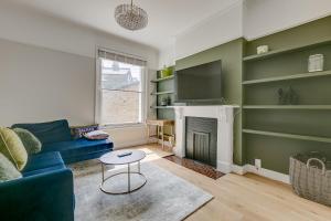 - un salon avec un canapé bleu et une cheminée dans l'établissement Boutique Victorian 4 Bed House with Garden in Balham, à Londres