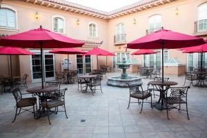 a courtyard with tables and chairs with red umbrellas at Carlton Hotel in Atascadero