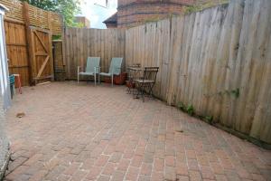 a patio with chairs and tables in front of a fence at 4 Bedroom House in Turnpike Lane/Wood Green in London