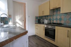 una cucina con lavandino e piano cottura forno superiore di 4 Bedroom House in Turnpike Lane/Wood Green a Londra