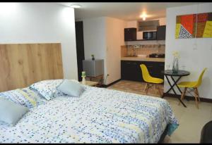 a bedroom with a bed and a kitchen with yellow chairs at CAMAKING /WIFI/ NETFLIX/ NORTE/ VALLEDEATRIZ/MODERNO in Pasto
