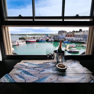 a window with a bottle of wine and glasses on a table at Padstow Escapes - Pajar Luxury Penthouse Apartment in Padstow