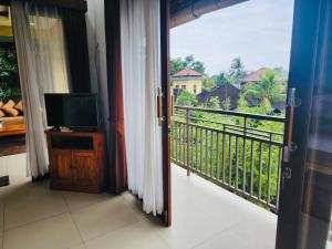 a room with a balcony with a television and a view at Uma Padi Villa in Ubud