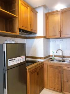 a kitchen with wooden cabinets and a stainless steel refrigerator at Ptas Tauch Residence in Phnom Penh