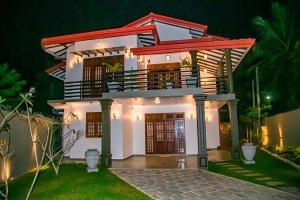 a house with a balcony at night at Chala Villa in Ambalangoda