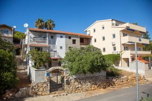 a white building next to a stone wall at Apartments by the sea Milna, Vis - 8895 in Rukavac