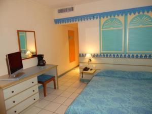 una camera da letto con un letto e una scrivania con un computer di Agréable studio avec terrasse et vue sur la Marina a Les Trois-Îlets