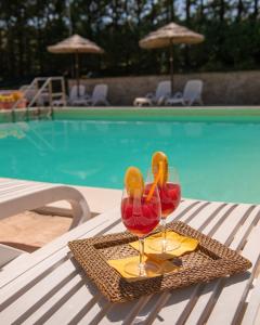 dos copas de vino tinto sentados en una mesa junto a una piscina en Boutique Country House Serendipity, en Cantiano