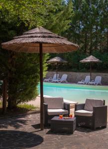 eine Terrasse mit 2 Stühlen und einem Sonnenschirm neben einem Pool in der Unterkunft Boutique Country House Serendipity in Cantiano