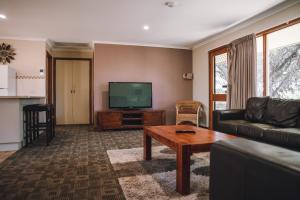 a living room with a couch and a flat screen tv at Riverbush Cottages in Monash
