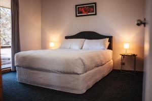 a hotel room with a large bed with two lamps at Riverbush Cottages in Monash