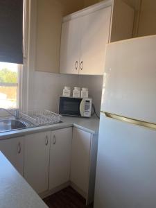 a kitchen with white cabinets and a white refrigerator at Commercial Travellers House in Gulgong