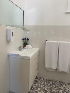 ein Badezimmer mit einem Waschbecken, einem Spiegel und Handtüchern in der Unterkunft Commercial Travellers House in Gulgong