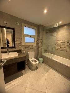 ein Badezimmer mit einem WC, einem Waschbecken und einer Badewanne in der Unterkunft Lovely Apartment New giza in Abū Rawwāsh