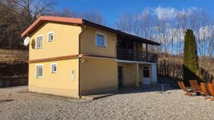 una pequeña casa amarilla sentada encima de un lote de grava en Family friendly house with a swimming pool Vrbovsko, Gorski kotar - 20331, en Vrbovsko