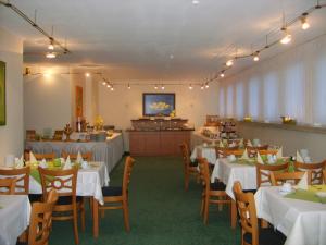 a dining room with white tables and chairs and a kitchen at City Hotel by celina in Hagen