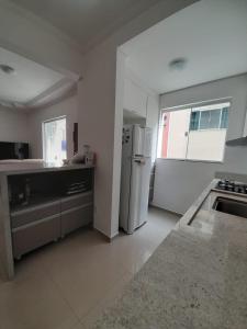 cocina blanca con nevera y fregadero en Apto novo com piscina e pátio na praia dos Ingleses, en Florianópolis