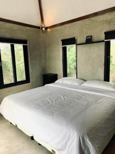 a bedroom with a large white bed with two windows at OCEANNA - Uluwatu, Bali in Uluwatu