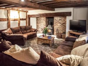 a living room with leather couches and a fireplace at Brookbank Farm in Jodrell Bank