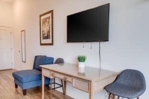 a desk with two chairs and a television on a wall at Unit 9 Maui Ohana Modern Studio in Wailuku