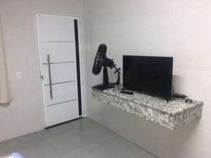 a room with a television sitting on a counter next to a door at POUSADA COM PISCINA em PERUÍBE SABORES DA VIDA!!! in Peruíbe