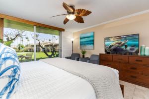 a bedroom with a bed with a ceiling fan and a tv at Napili Shores G157 condo in Kahana