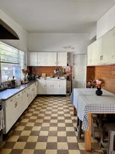 a kitchen with white cabinets and a checkered floor at Espectacular casa hostal en Barrio Italia in Santiago