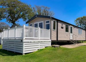 a small house with a white fence in the grass at Orchards Holiday Park in Newbridge