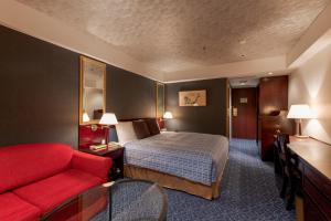 横浜市にあるローズホテル横浜のベッドと赤い椅子が備わるホテルルームです。