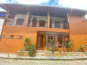 - un bâtiment orange avec un balcon orné de plantes dans l'établissement Samburá Paraty, à Parati