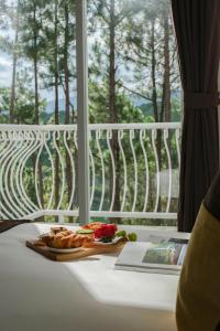 ein Teller mit Essen auf einem Tisch neben einem Fenster in der Unterkunft CEREJA Hotel & Resort Dalat in Da Lat