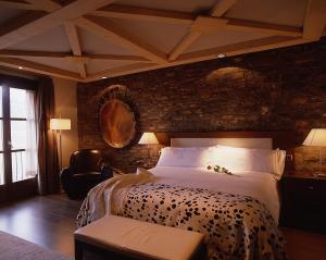 um quarto com uma cama grande e uma parede de tijolos em Los Siete Reyes em Aínsa